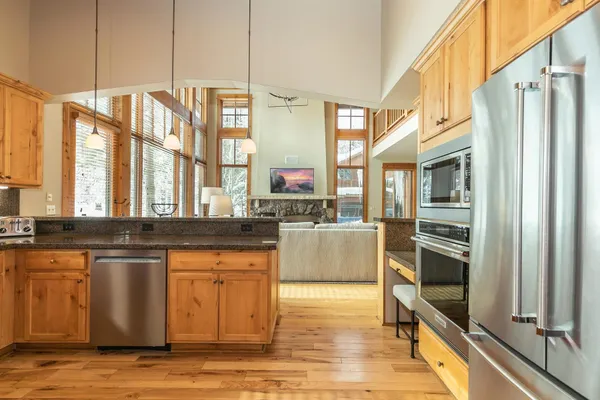 a kitchen with stainless steel appliances granite countertop a refrigerator a stove and a sink with wooden floor