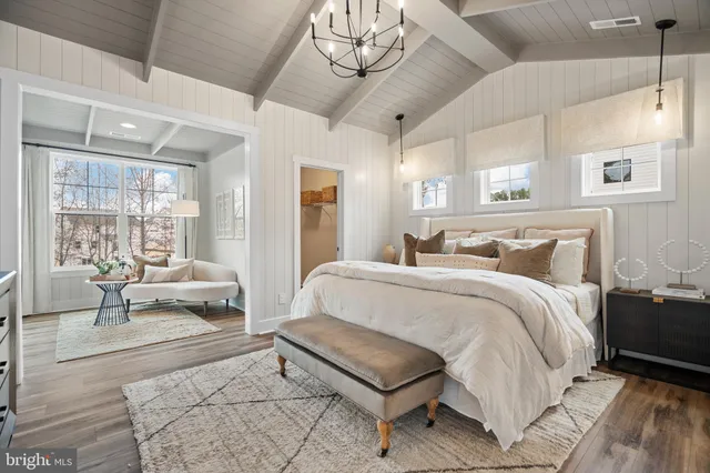 a spacious bedroom with a bed a chandelier and couches