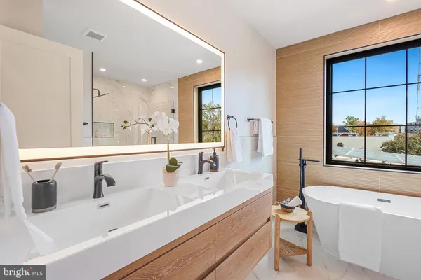 a bathroom with a tub a sink and a large window