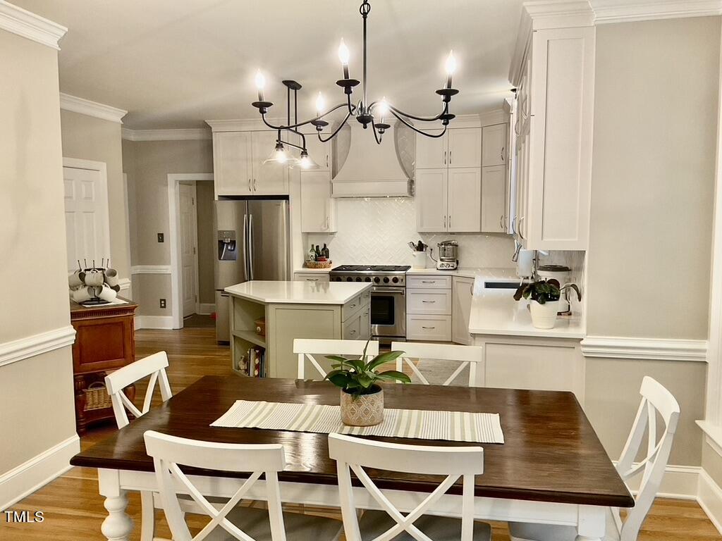 4209 Old Lewis Farm Road Raleigh, NC 27604 - Photo 6 of 47 a kitchen with a dining table chairs and white cabinets
