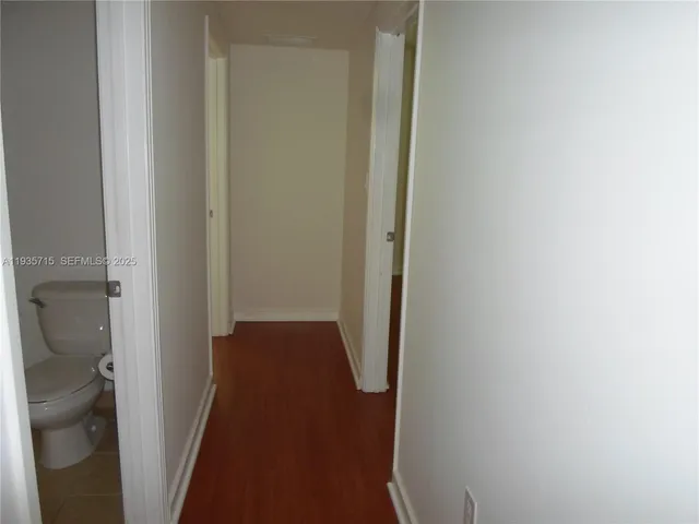 a view of a big room with wooden floor and a kitchen