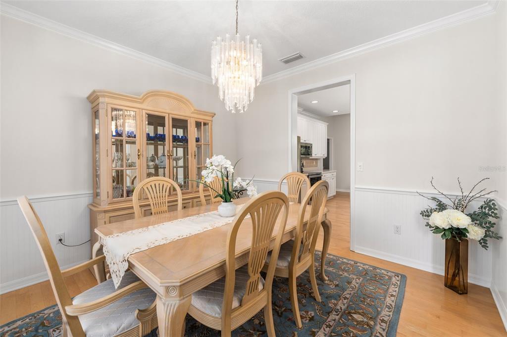 7418 White Oaks Road Alachua, FL 32615 - Photo 7 of 46 a dining room with wooden floor a chandelier a wooden table and chairs
