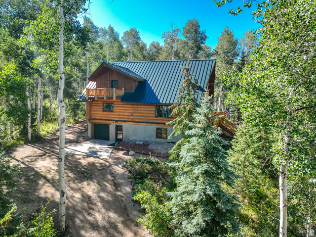 11192 Maple Road, Unit 7 Heber City, UT 84032 - Photo 39 of 51 Log cabin exterior featuring a metal roof, an upper-level balcony, a wooden staircase, and a drive-under garage
