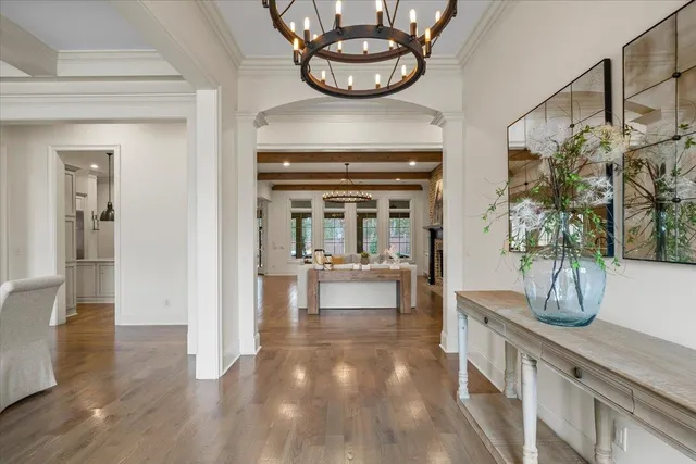 a view of a hallway with wooden floor and a chandelier