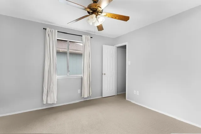 an empty room with a ceiling fan and carpet