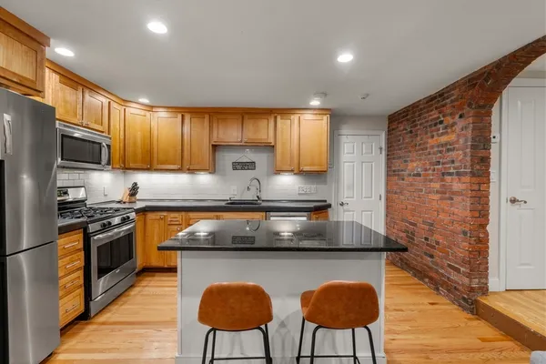 a kitchen with stainless steel appliances granite countertop a sink wooden cabinets and a stove top oven
