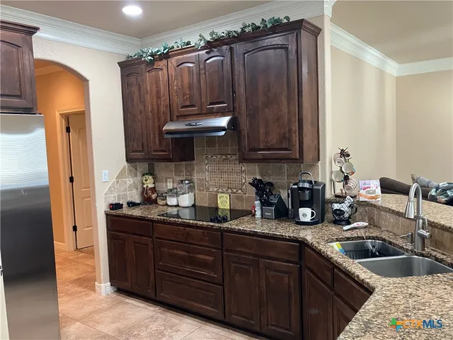 a kitchen with granite countertop a sink cabinets and stainless steel appliances