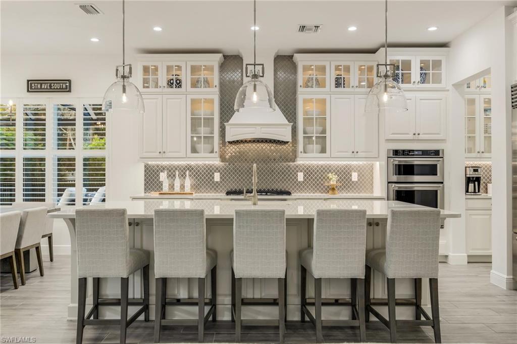 3664 Pilot Circle Naples, FL 34120 - Photo 13 of 35 a kitchen with stainless steel appliances granite countertop a table chairs stove and cabinets
