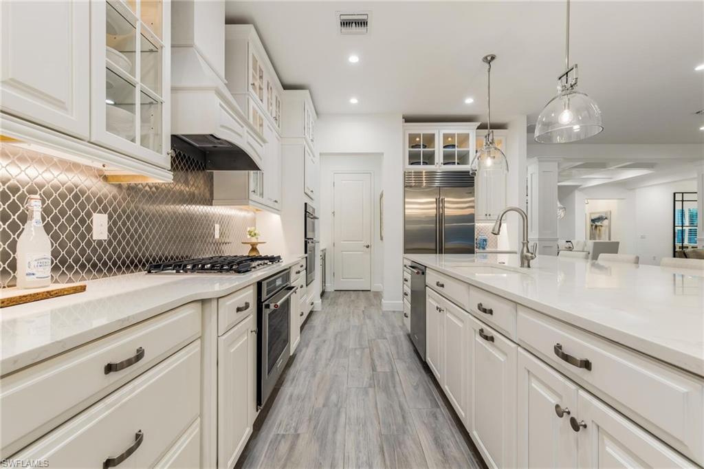3664 Pilot Circle Naples, FL 34120 - Photo 15 of 35 a large kitchen with granite countertop a large kitchen island white cabinets and stainless steel appliances