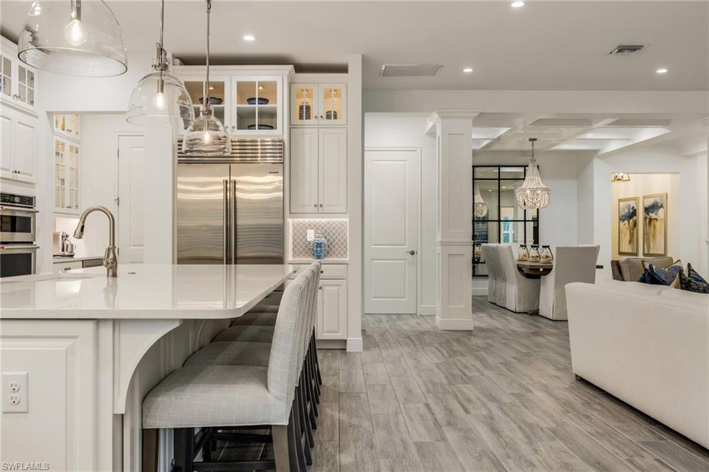 3664 Pilot Circle Naples, FL 34120 - Photo 17 of 35 a kitchen with stainless steel appliances a refrigerator a sink a stove and white cabinets with wooden floor