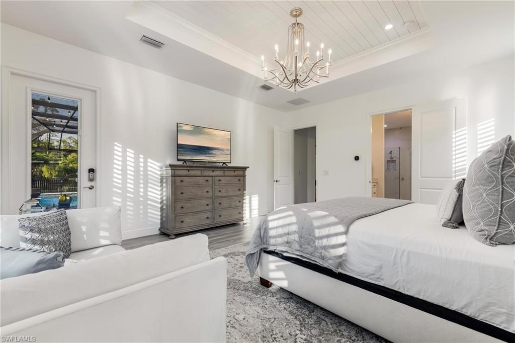 3664 Pilot Circle Naples, FL 34120 - Photo 25 of 35 a bedroom with a large bed a chandelier and dresser