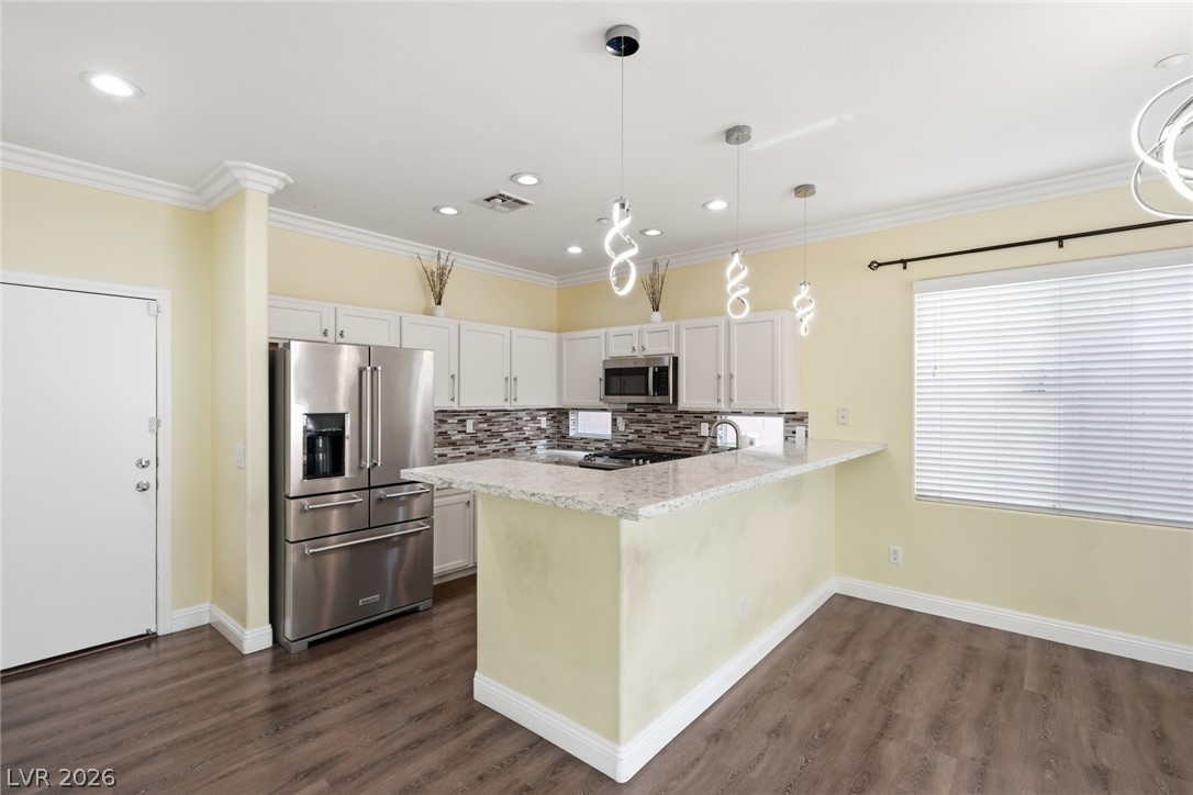 8932 Caledon Ridge Court Las Vegas, NV 89149 - Photo 3 of 39 Warm wood flooring pairs with granite counters in this modern, light-filled kitchen space.