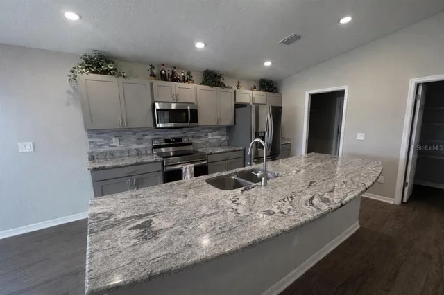 a kitchen with kitchen island a sink stainless steel appliances and cabinets