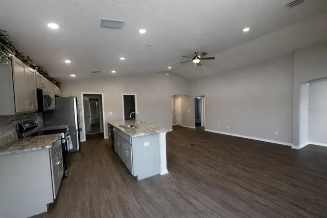 a large kitchen with stainless steel appliances a large counter top a sink a stove a refrigerator and a window