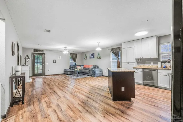 a living room with stainless steel appliances furniture a kitchen view and a refrigerator