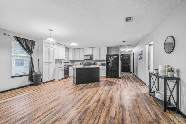 a large white kitchen with wooden floors and wooden cabinets