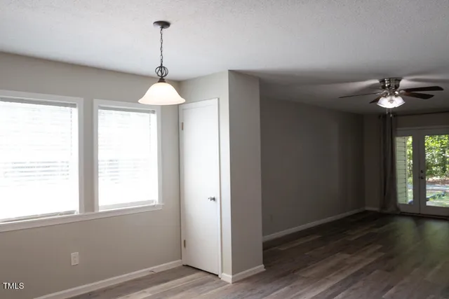 an empty room with wooden floor fan and windows