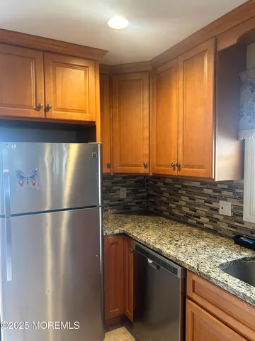 a kitchen with granite countertop a refrigerator a sink and dishwasher with wooden floor