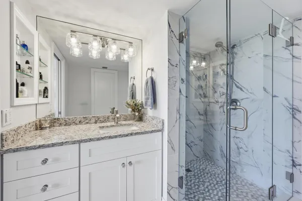 a bathroom with a granite countertop sink vanity mirror next to a window