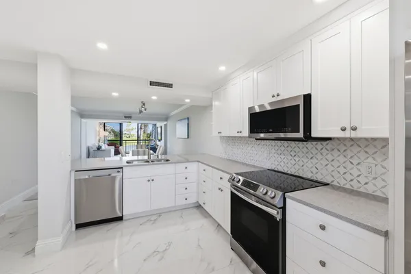 a kitchen with granite countertop white cabinets and stainless steel appliances
