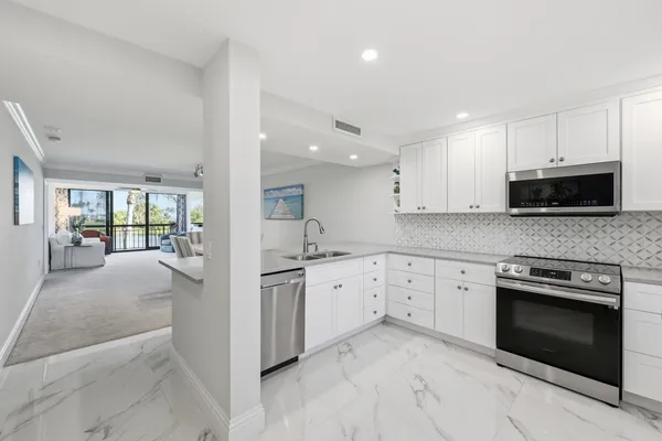 a kitchen with granite countertop white cabinets and stainless steel appliances