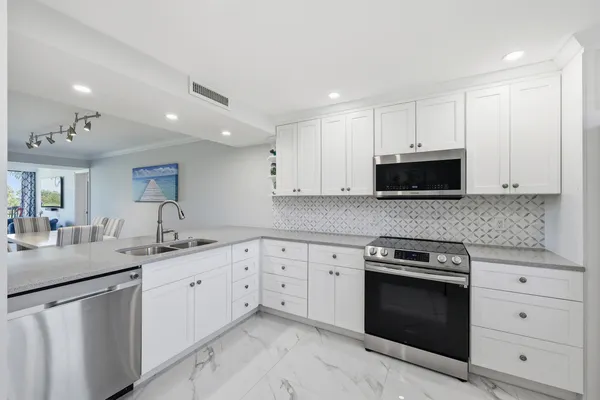 a kitchen with granite countertop white cabinets and stainless steel appliances