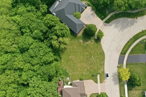 an aerial view of a house with a yard and trees all around