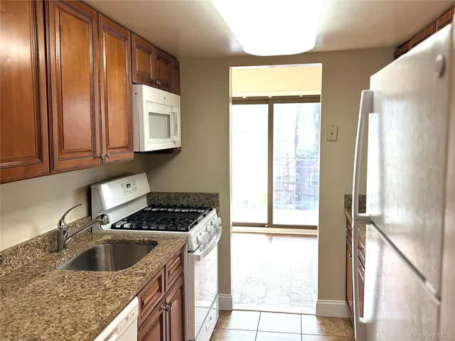 a kitchen with granite countertop stainless steel appliances a sink a refrigerator and a window