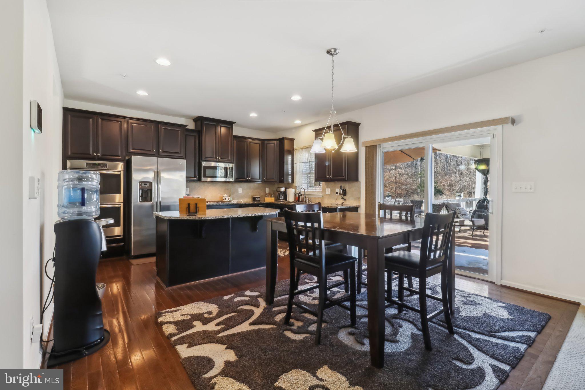 14013 Wheel Wright Place Accokeek, MD 20607 - Photo 11 of 38 a kitchen with stainless steel appliances granite countertop a refrigerator a stove a sink a dining table and chairs with wooden floor