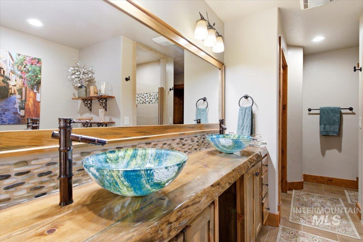 1029 Cee Way Loop McCall, ID 83638 - Photo 21 of 50 Wood-finish cabinetry with glass panel doors, dual basin stainless steel sink with a matte black faucet, integrated beverage coolers, and stone countertops
