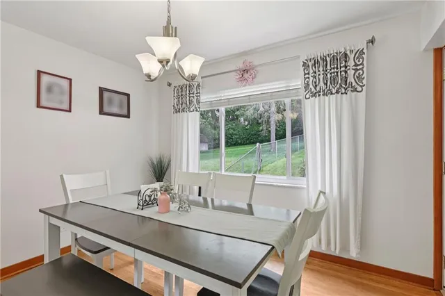 a dining room with wooden floor and a chandelier