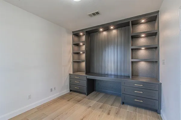 a view of an empty room with cabinet and wooden floor