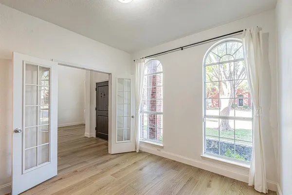 a view of an empty room with wooden floor and a window