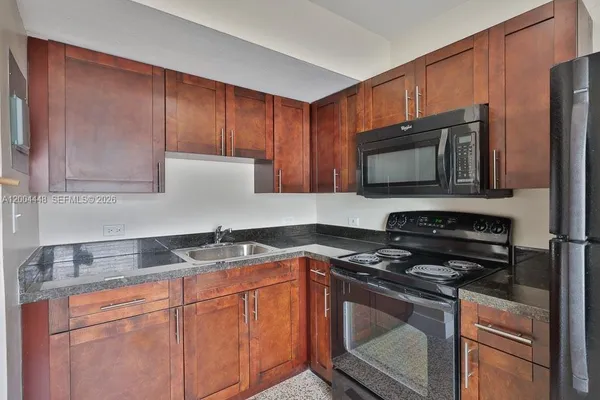a kitchen with granite countertop a sink stove and microwave