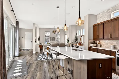 a kitchen with stainless steel appliances a kitchen island hardwood floor sink stove and living room view