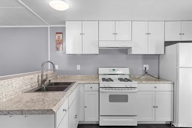 a kitchen with granite countertop a sink a stove and cabinets