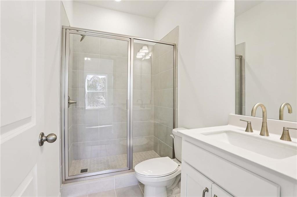 6155 Kismet Road Buford, GA 30518 - Photo 19 of 47 a bathroom with a shower sink vanity mirror and toilet