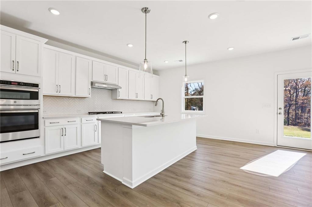 6155 Kismet Road Buford, GA 30518 - Photo 9 of 47 a kitchen with stainless steel appliances granite countertop a wooden floors a stove a sink and white cabinets