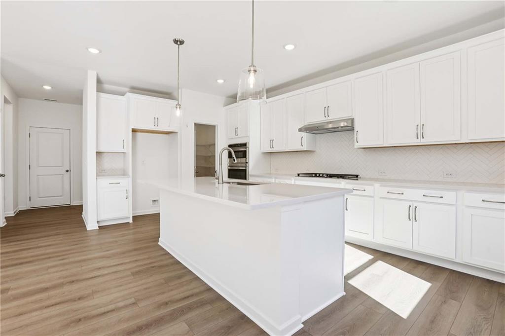 6155 Kismet Road Buford, GA 30518 - Photo 10 of 47 an open kitchen with white cabinets and stainless steel appliances