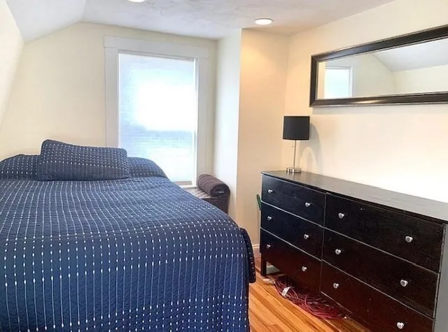 a bedroom with a bed and a dresser with mirror