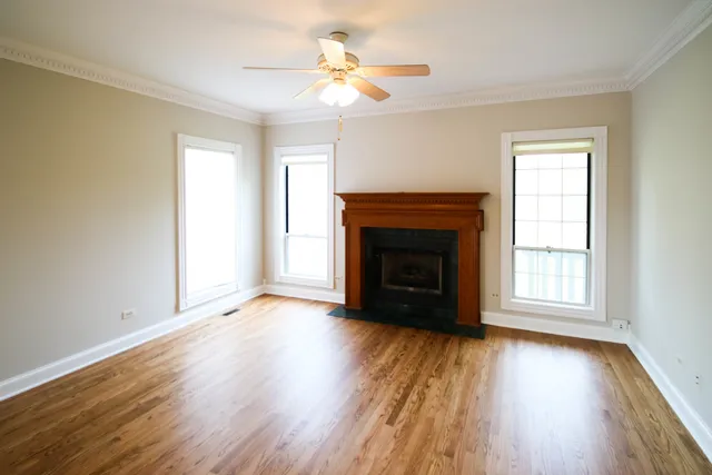an empty room with wooden floor fireplace and windows