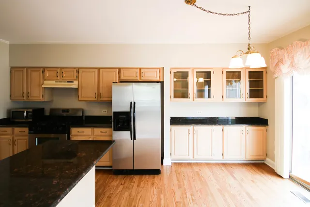 a kitchen with stainless steel appliances granite countertop a refrigerator a stove and a sink with wooden floor