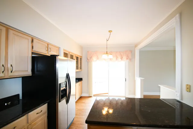 a kitchen with stainless steel appliances granite countertop a refrigerator a stove and a sink with wooden floor