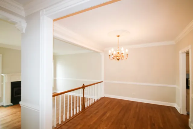 a view of a hallway with wooden floor and a chandelier