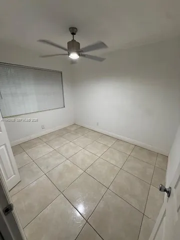 an empty room with a ceiling fan and carpet