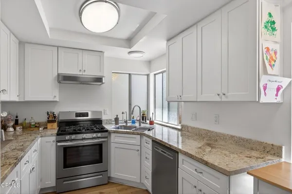 a kitchen with granite countertop a sink stainless steel appliances and cabinets