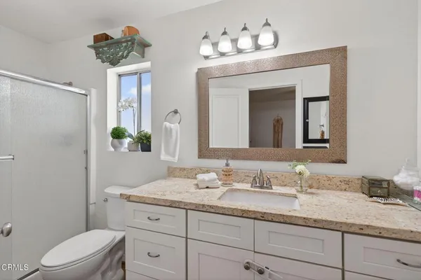 a bathroom with a granite countertop sink a toilet and mirror