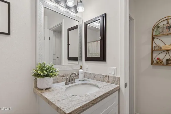a bathroom with a granite countertop sink and a mirror
