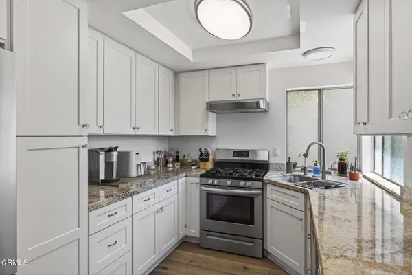 a kitchen with granite countertop white cabinets and white appliances