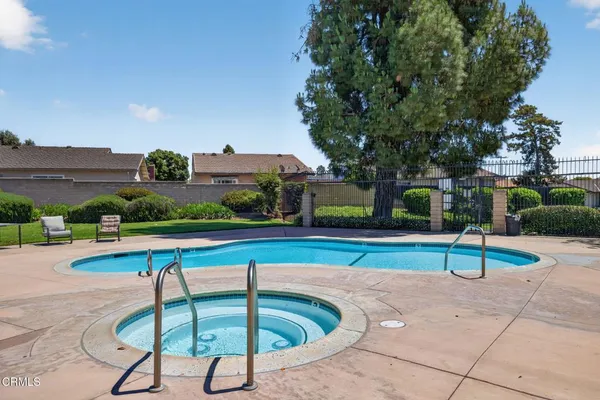 a view of pool with lawn chairs and plants